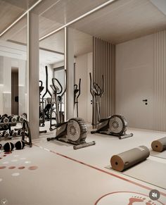 there are many exercise machines in the room with yoga mats on the floor next to them