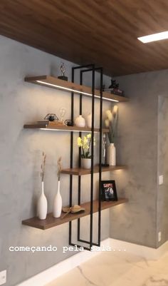 some shelves with vases and flowers on them in a room that is painted white