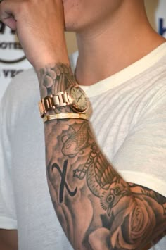 a man with tattoos on his arm and wrist is holding his hand to his face