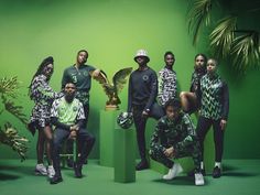 a group of people posing for a photo in front of a green wall with an eagle statue