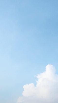 two people standing on the beach flying a kite in the blue sky with white clouds