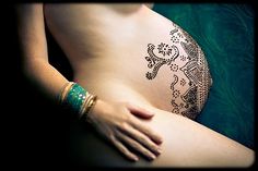 a woman's arm with a tattoo on it and her hand resting on the belly