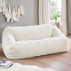 a large white couch sitting on top of a hard wood floor next to a window