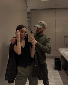 a man standing next to a woman taking a selfie in a bathroom with a mirror