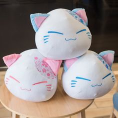 two white cat pillows sitting on top of a wooden table in front of a television