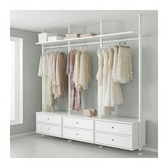 an organized closet with white drawers and hanging clothes