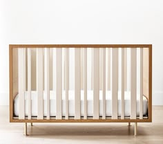 a wooden crib with white sheets on the bottom and one mattress in the middle