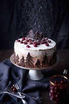 a cake with white frosting and cranberries on top sitting on a table