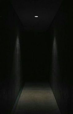 an empty dark hallway with light at the end