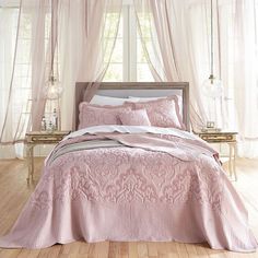 a bedroom with pink bedding and curtains