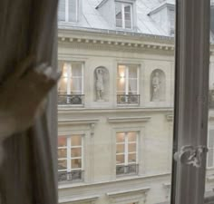 an open window looking out onto a building with statues on the windowsill and outside