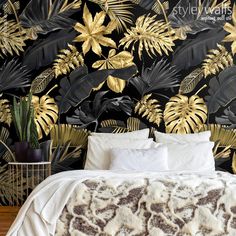 a bed sitting next to a wall covered in gold leafy plants and foliages