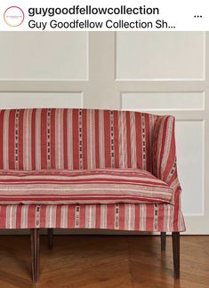 a red and white striped couch sitting on top of a hard wood floor next to a wall