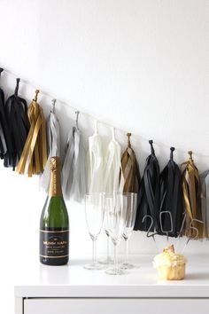 a table with wine glasses, champagne bottle and tassels hanging from the wall