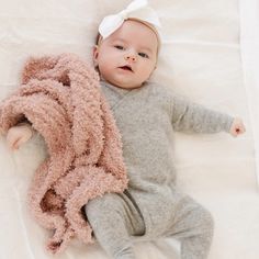 a baby laying on top of a bed next to a blanket