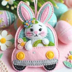 an ornament shaped like a bunny driving a pink car with flowers in the background