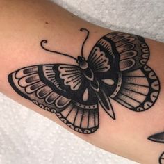 a black and white butterfly tattoo on the arm