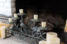 candles are lit in front of a fireplace with birds and flowers on the mantel