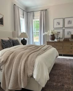 a large bed sitting in a bedroom next to a window with curtains on the windowsill