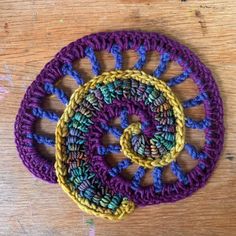 two crocheted coasters sitting on top of a wooden table