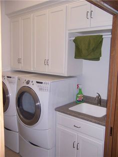 a washer and dryer in a small laundry room with white cabinets, counter tops and drawers