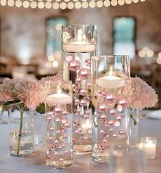 the centerpieces are filled with pink flowers and lit candles in glass vases