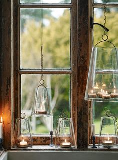 candles are lit in glass containers on a window sill