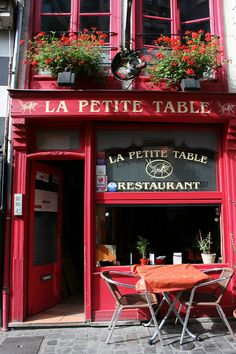 a table and chairs in front of a red building