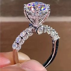 a close up of a person holding a diamond ring with diamonds on the band and side stones