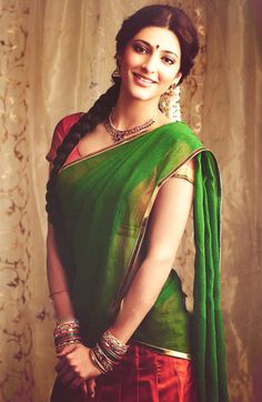 a woman in a green and red sari posing for the camera with her hands on her hips