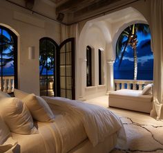 a large bed sitting in a bedroom next to an open window with the ocean view