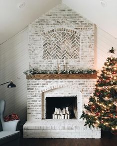 a decorated christmas tree in front of a brick fireplace