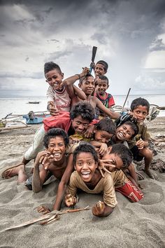 a group of children are posing for a photo on the beach with baseball bats in their hands