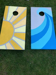 two painted cornhole boards sitting on top of a grass covered field next to each other