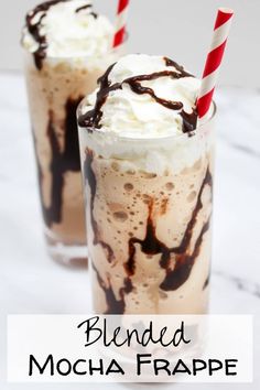 two glasses filled with ice cream and topped with whipped cream, chocolate syrup and candy canes