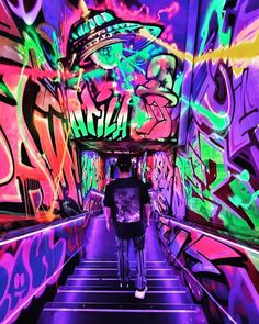 a person riding a bike down a tunnel covered in colorful grafitti art on the walls