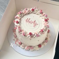 a white cake with pink flowers and the word thirty on it in a box that is open