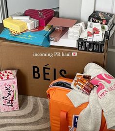 an open box with various items in it sitting on the floor next to a pile of books