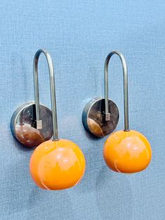 two metal hooks with orange balls attached to them