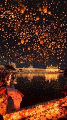 many lanterns floating in the air over water