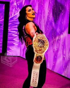 a woman holding a wrestling belt in front of a purple background