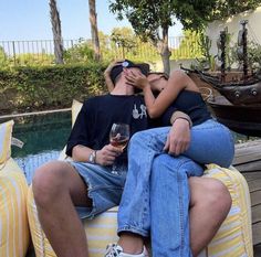 a man and woman sitting on top of each other with wine glasses in their hands