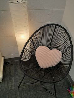 a heart shaped pillow sitting on top of a black chair next to a light bulb