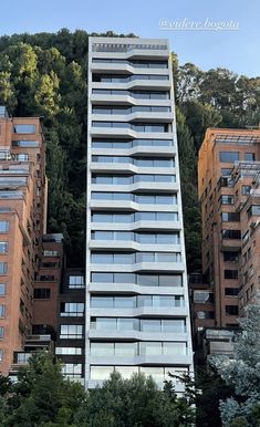 a tall building with balconies on top of it's sides in front of some trees