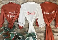 three bride robes hanging up against a brick wall