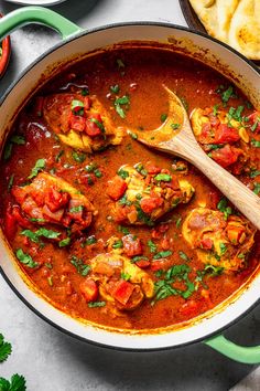 a pan filled with chicken and tomato stew next to tortilla chips on the side