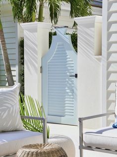 an outdoor area with white furniture and palm trees on the side walk, along with a blue door