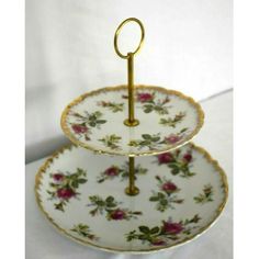 two tiered trays with roses on them, each holding a gold ring handle