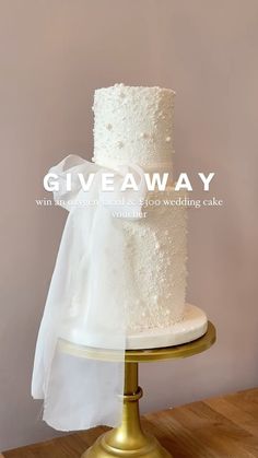 a three tiered wedding cake on a gold stand with the words giveaway written above it