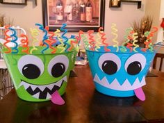 two buckets decorated with monster faces and streamers on a table in a dining room